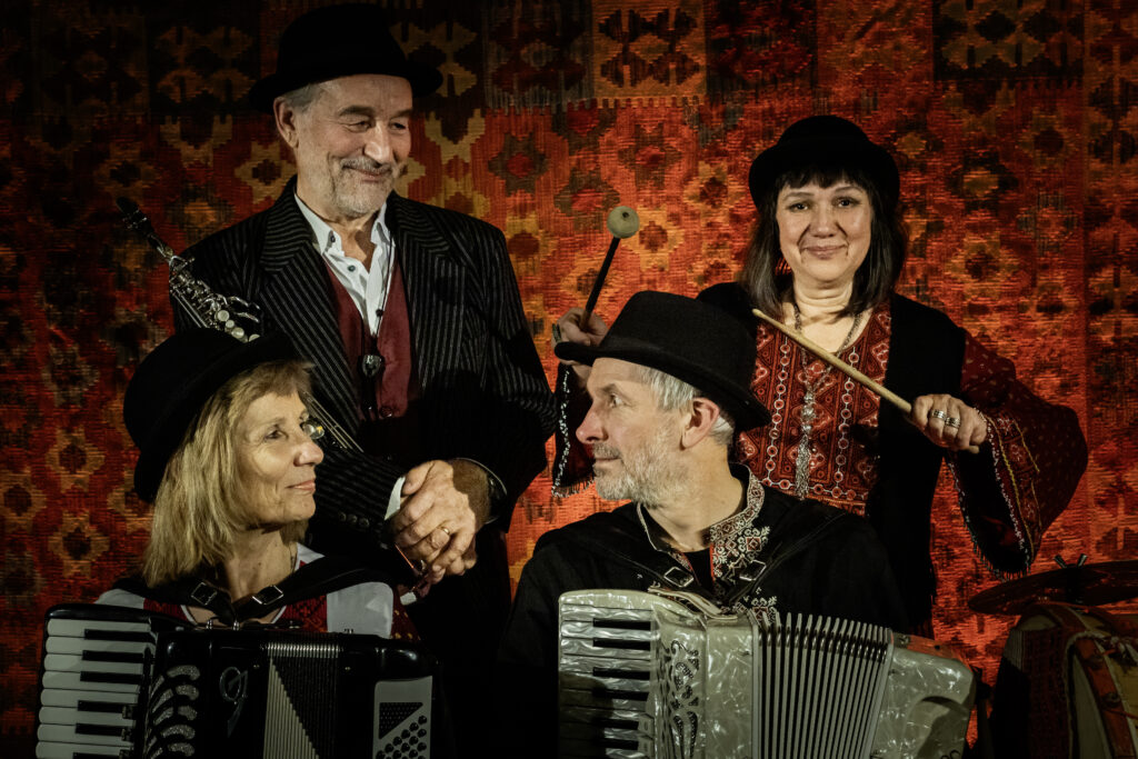 Czterech muzyków w tradycyjnych strojach i kapeluszach.